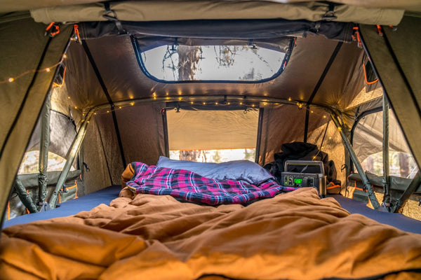 Interior of Vagabond XL Rooftop Tent with sheets, lights, and skylight